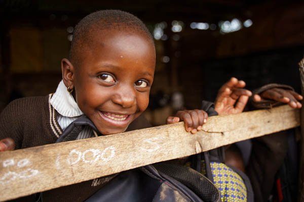 A smiling child in a window seeing outside